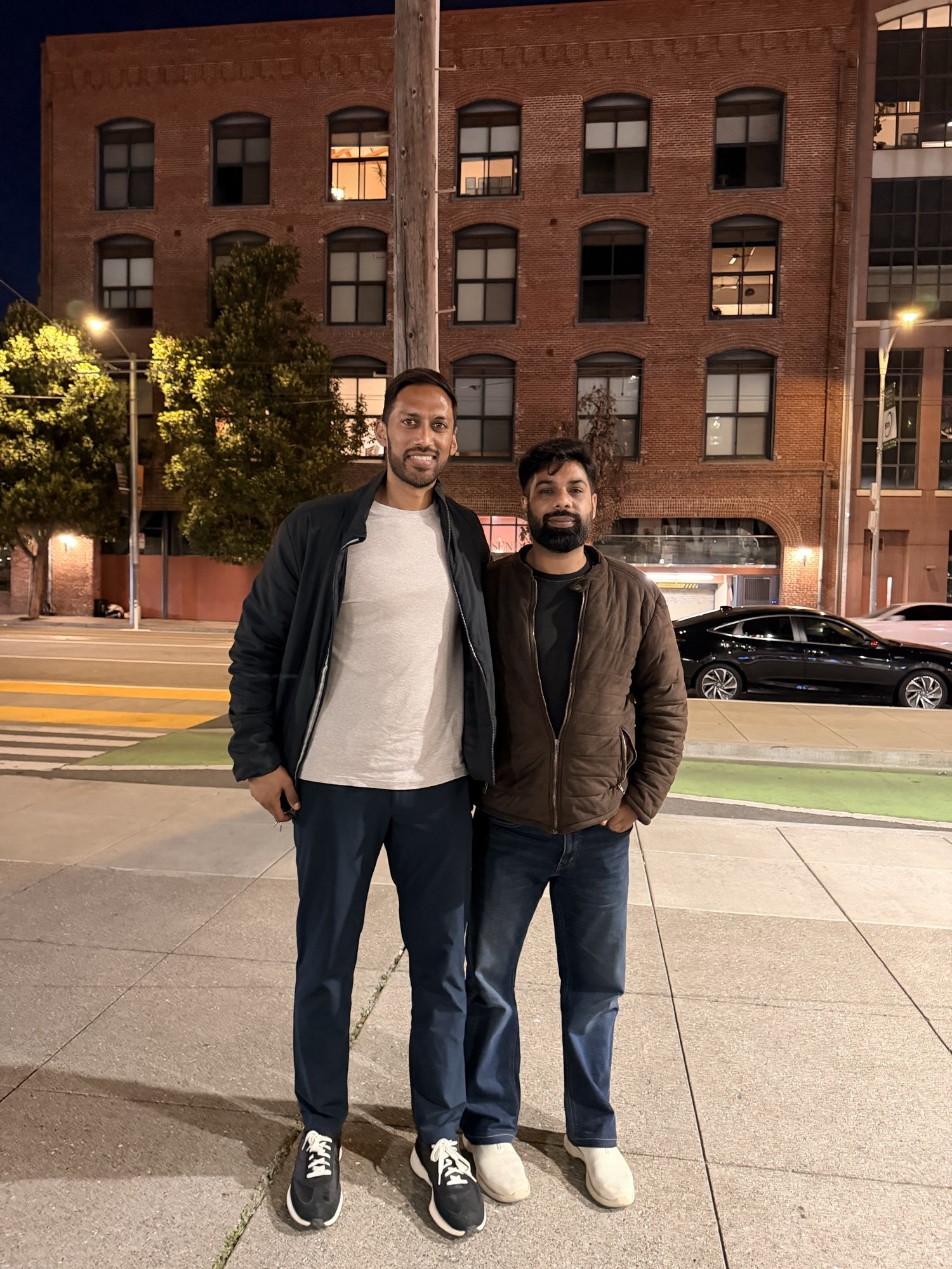 Two men standing together on a San Francisco sidewalk at night.
